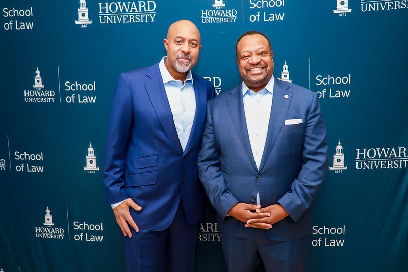 Roy L. Austin, Jr. and Dean Roger A. Fairfax, Jr. standing together in front of a Howard University School of Law backdrop.
